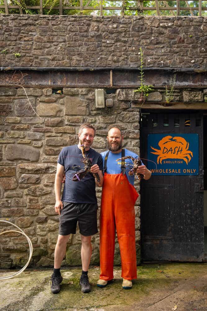 Anthony and Danny posing for a photo holding some lobsters