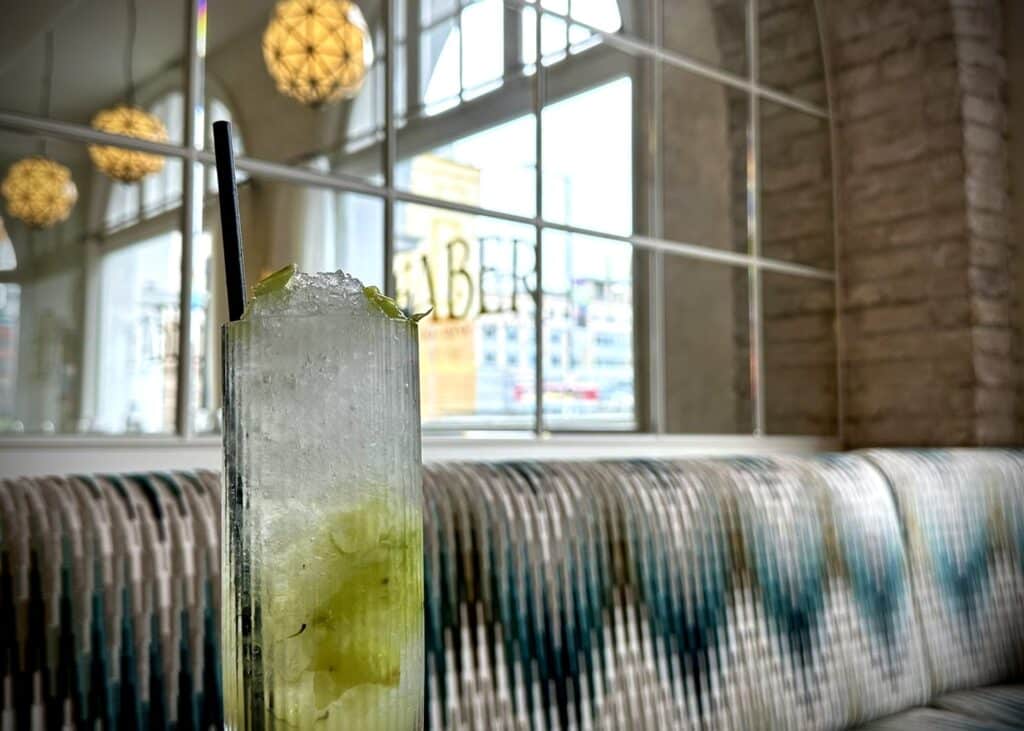 ridged highball glass on a table with a mirror behind and wave patterned seating.
