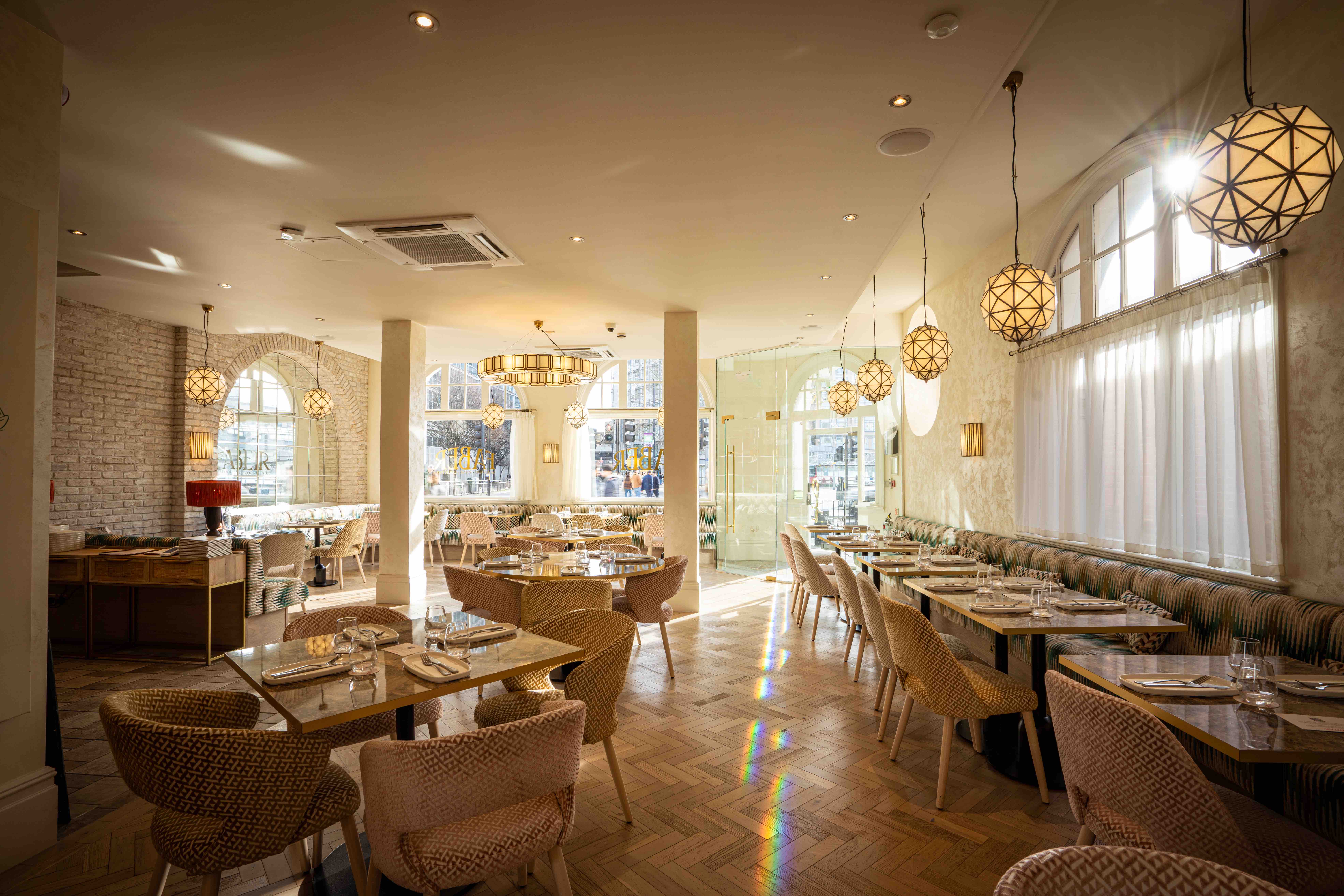 Faber restaurant with bright sunlight beaming through the large arched windows, casting light across the airy interior and coastal inspired furniture.