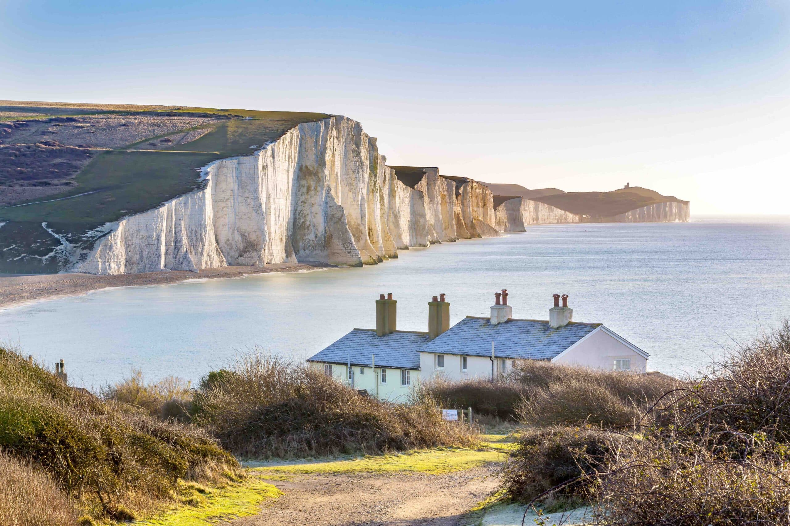 The Coast Guard Cottages in foreground; Seven Sisters Chalk Cliffs just outside Eastbourne in the rear on a bright clear spring day, Sussex, England.