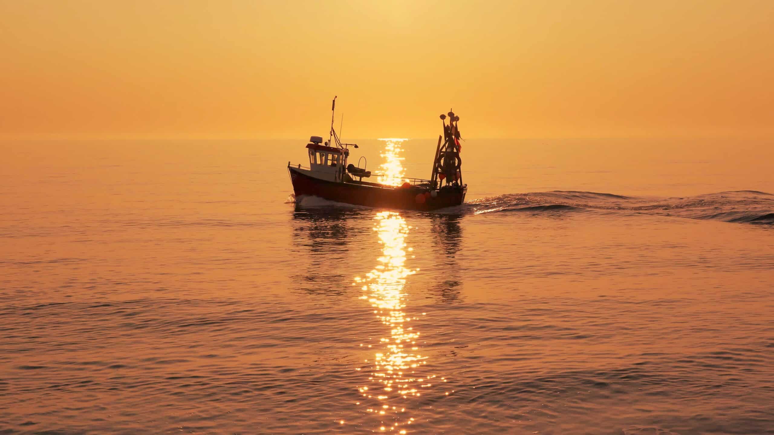 Fishing boat on a calm sea in early morning autumnal sunlight.