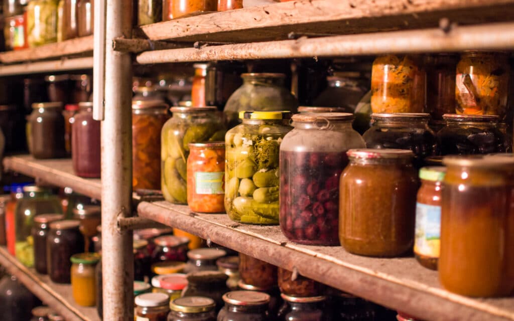 Kilner and glass jars on industrial, old metal shelves in a pantry full of picked and jam ingredients ready for winter and explained by Faber